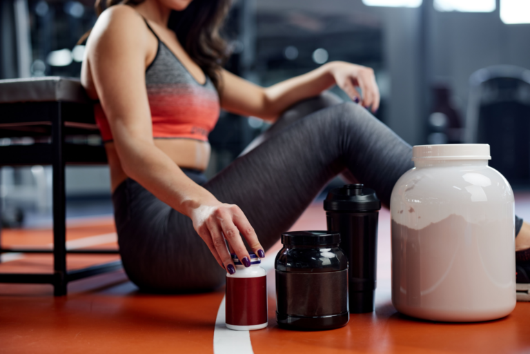 Woman in athletic clothing with dietary supplements and protein powder